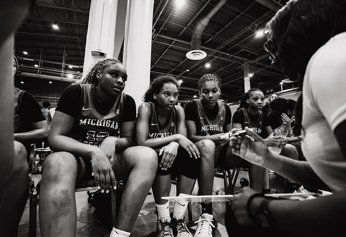 Female basketball players listening to their coach on the sideline